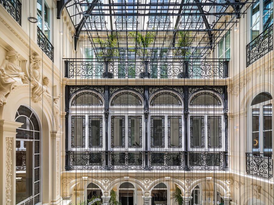 Un atrium à plusieurs niveaux, agrémenté de balustrades en fer forgé ouvragées, de grandes fenêtres et de détails architecturaux classiques.