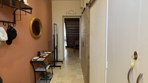 A hallway with a wooden door, a welcome sign, a mirror, and a table with items on it. - Logis de la Foulerie (Bize-Minervois)