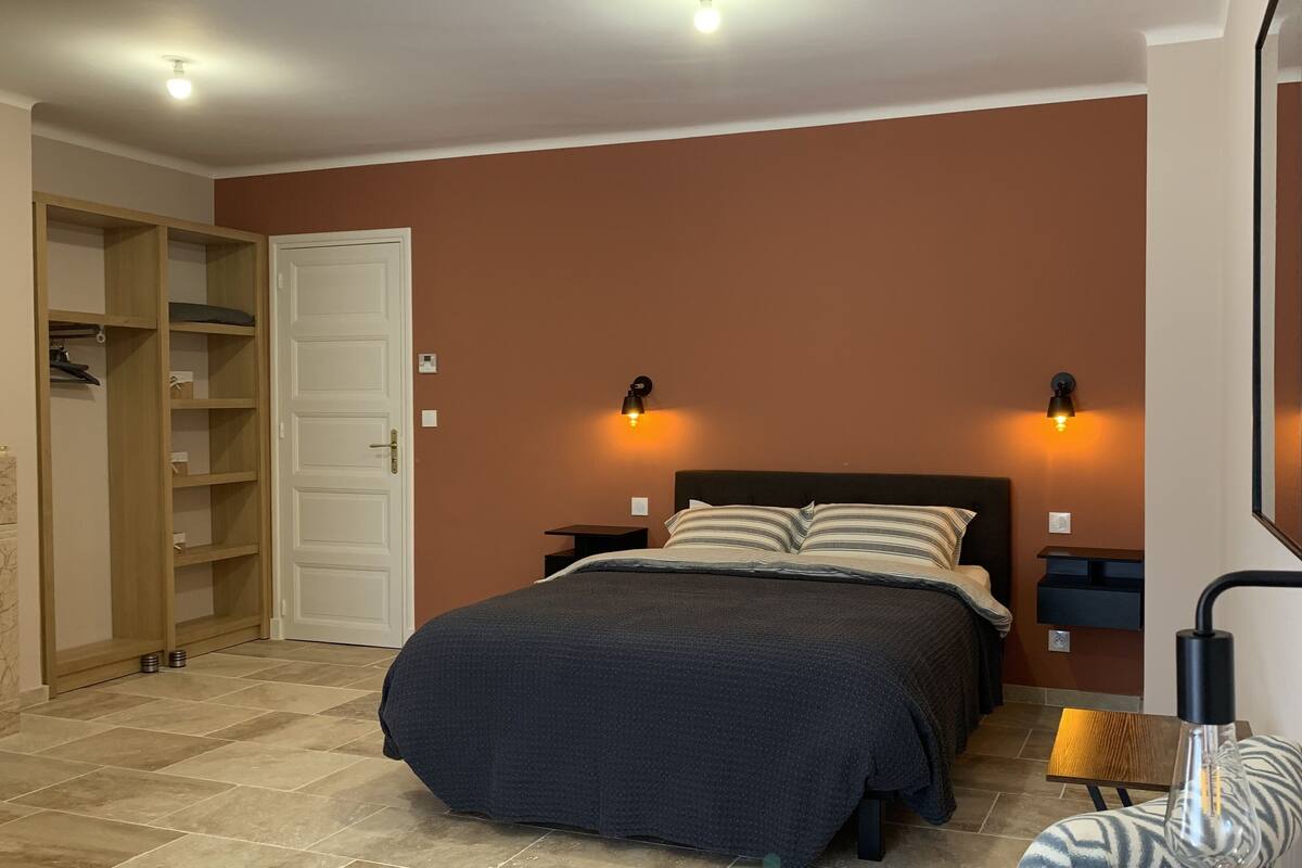 Ein Schlafzimmer mit einem Bett, zwei Nachttischen, einem Kleiderschrank und einem Spiegel.