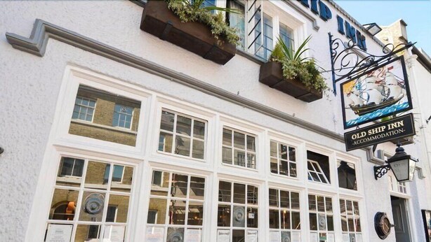A building with multiple windows, some with signs, and a signboard for 'Old Ship Inn' accommodation. - Old Ship Inn (Dorchester)