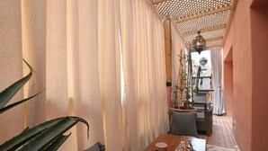 A narrow hallway with a wooden table, a potted plant, and a dining area in the background. - Jolie Appart-centre Gueliz (Marrakesh)