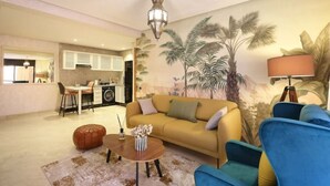 A living room with a sofa, ottoman, and chairs, a dining area with a table and chairs, and a kitchen with cabinets and a stove. - Jolie Appart-centre Gueliz (Marrakesh)