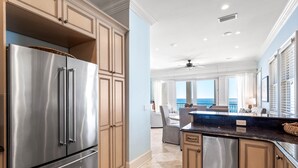 A modern kitchen with stainless steel appliances, beige cabinetry, and a view to the living area. - The Brookie*OnBeach*BeachSvc*Elevator*2Pools (Miramar Beach)