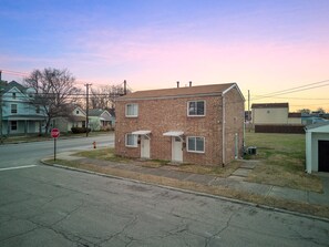 A small, single-story brick building with a white door and windows, located at a street corner with a stop sign visible. - My old Kentucky Home  (Louisville)