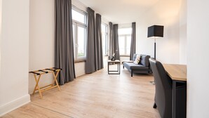 A modern living room with a wooden floor, a grey sofa, a small table, and a black lamp. - Homaris Strandhaus Blankenese (Hamburg)