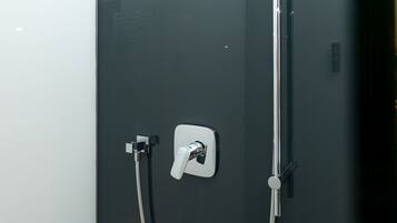 Une douche moderne dotée d’un pommeau de douche à main et d’un panneau de commande fixé au mur.