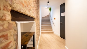 A staircase with wooden steps and a handrail, leading to a dark door with a sign. - Homaris Strandhaus Blankenese (Hamburg)