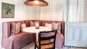 A cozy corner with a round table, a cushioned bench, and a hanging light fixture.