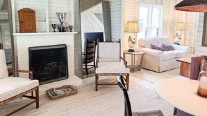 A cozy living room with a fireplace, a staircase, and a comfortable seating area.