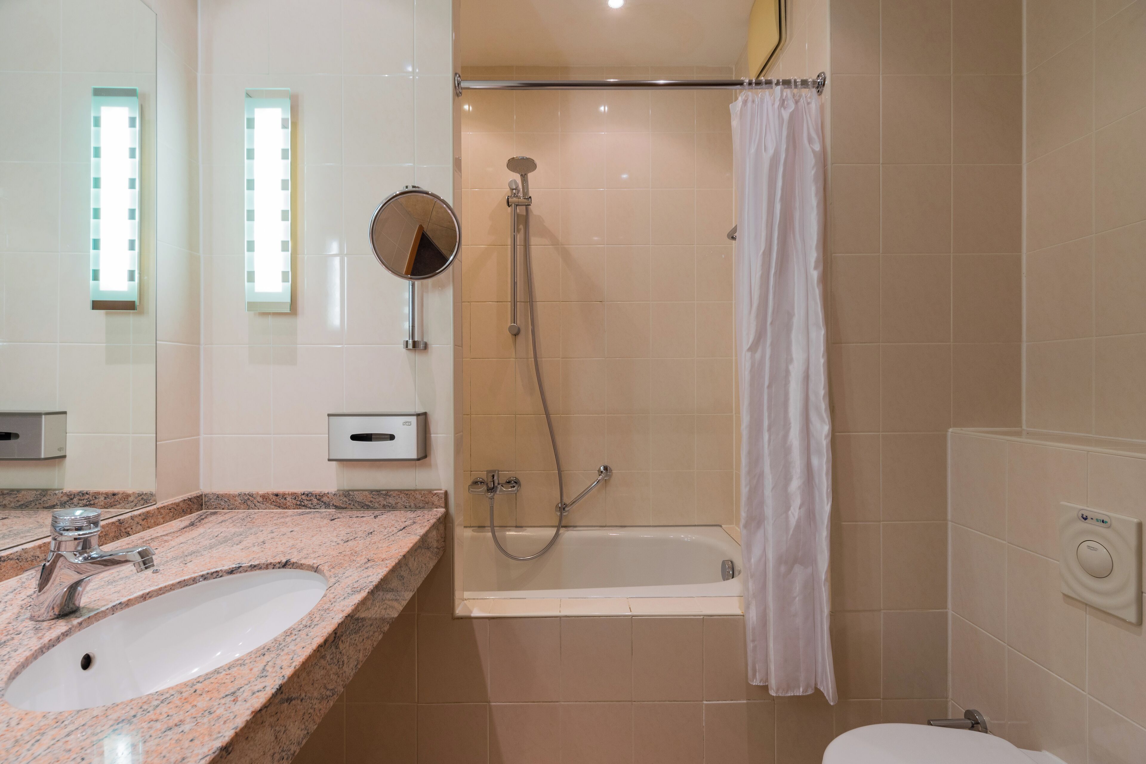 Une salle de bain équipée d’un lavabo, d’un miroir, d’une douche et de toilettes.