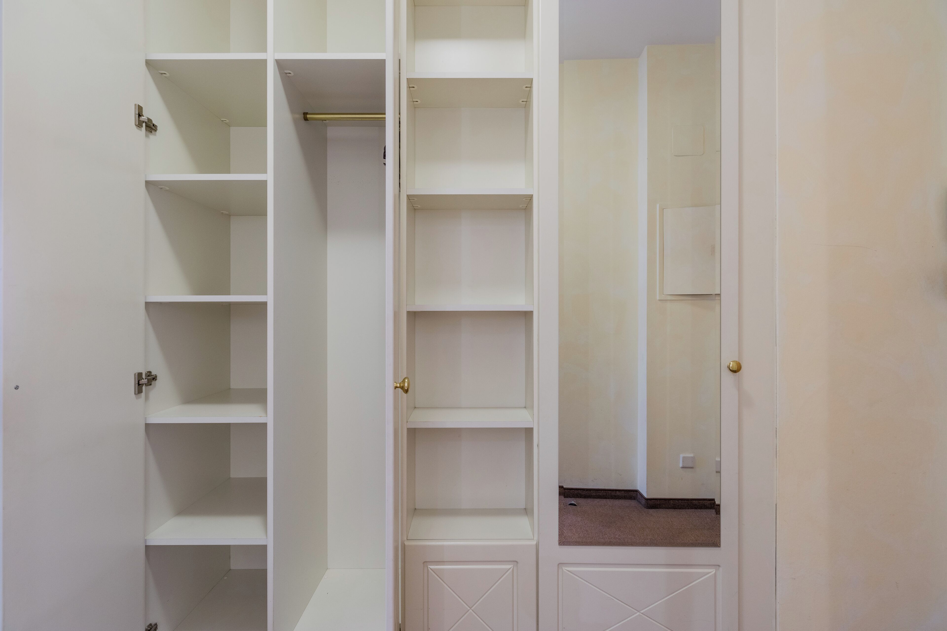 A white closet with multiple shelves and a door.
