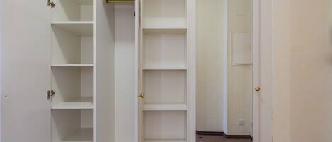 A white closet with multiple shelves and a door.