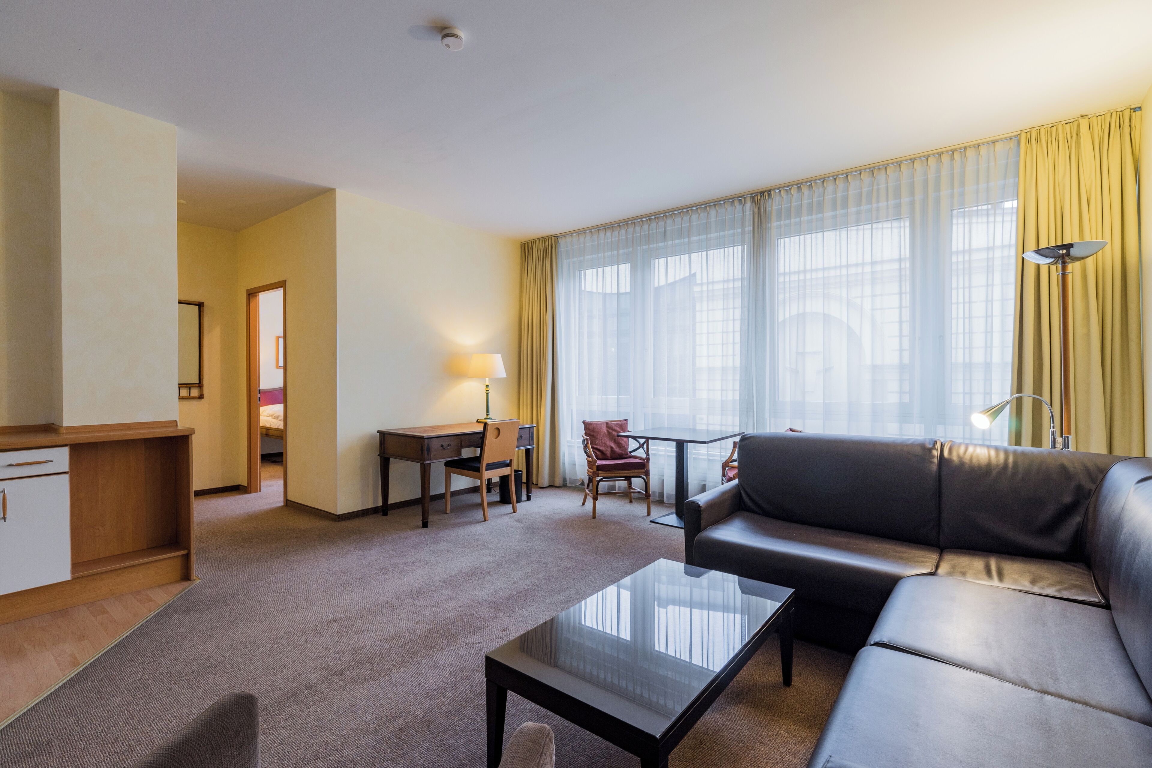 Une chambre d’hôtel moderne comprenant un coin salon, un bureau, un canapé et une table à manger.