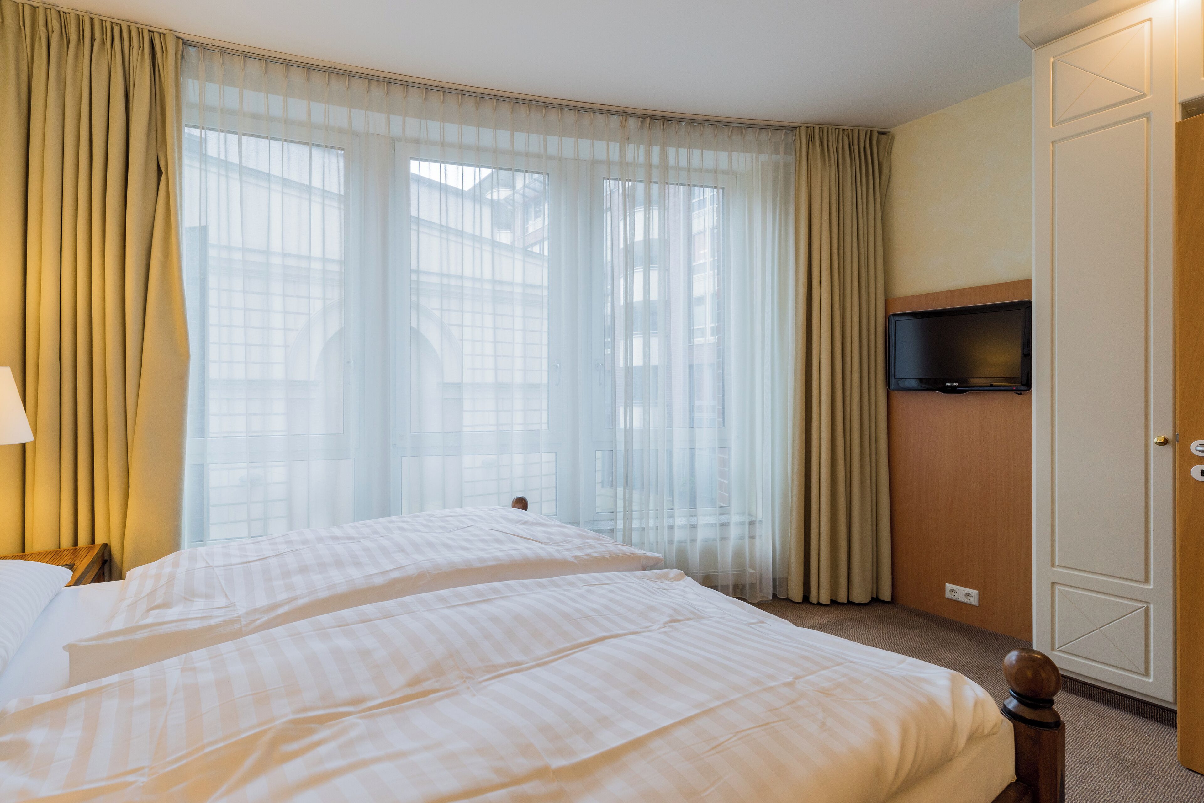 Habitación de hotel con dos camas, televisión y armario.