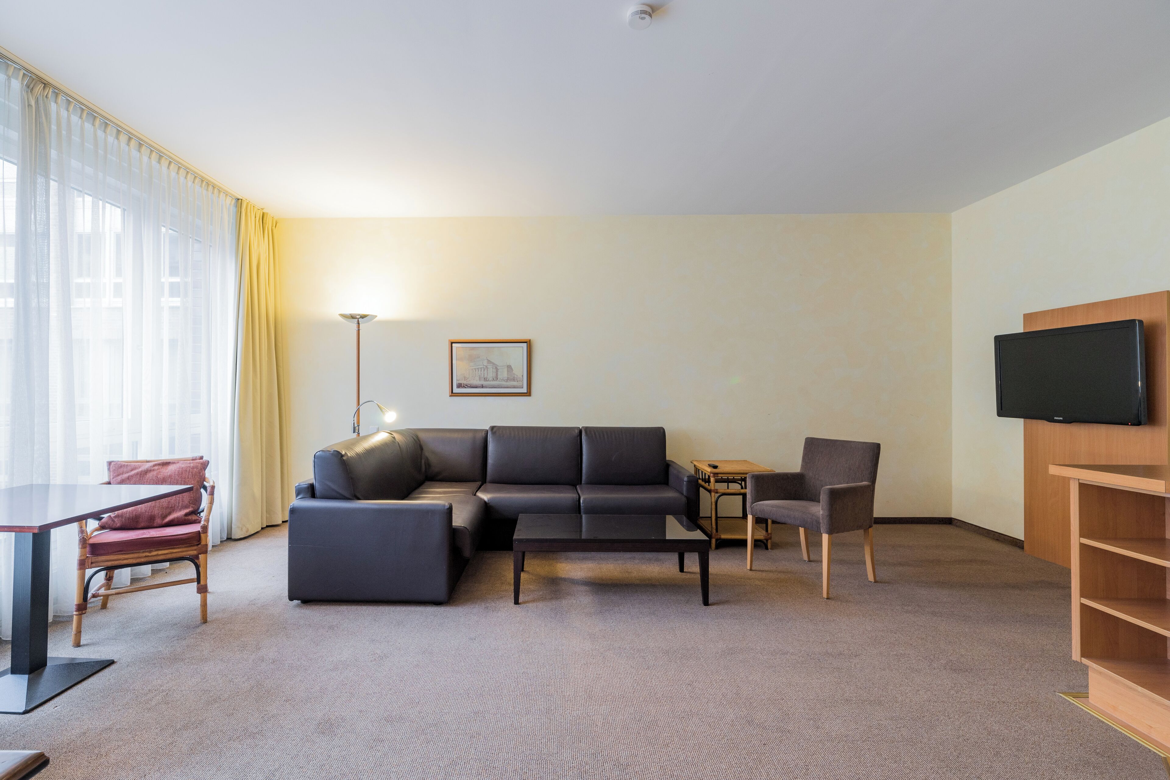En moderne stue med en sofa, et sofabord, et fjernsyn og en lampe.