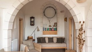 A cozy reading nook with a cushioned bench, a bookshelf, a wall clock, and a radiator.