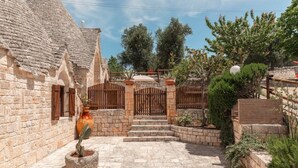 A courtyard with stone walls, a wooden gate, and potted plants.