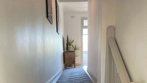 A wooden staircase with a handrail, leading to a door at the end. - Stay on Summer | CBD Apartment (Orange)