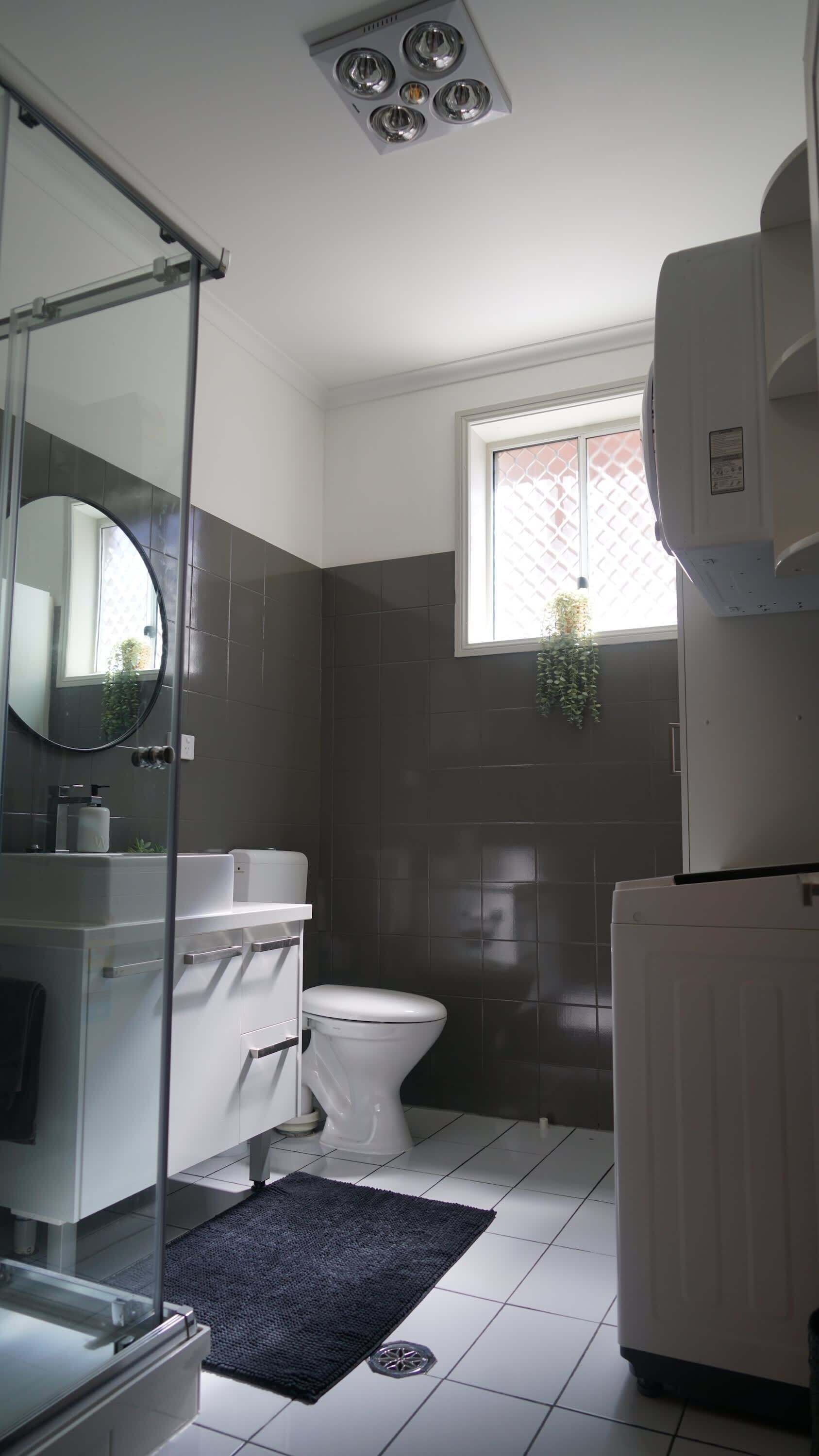 Une salle de bain avec des toilettes, un lavabo, un miroir et une fenêtre.