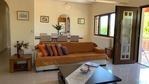 A modern living room with a sofa, coffee table, and dining area. - Stunning 3-bedroom Villa Near Malia Beach (Agios Nikolaos)