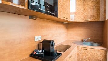 Uma cozinha compacta com micro-ondas embutido, máquina de café, pia e armários de madeira.