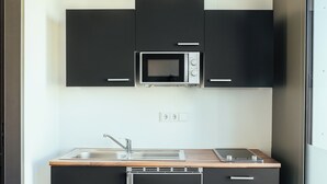Eine kleine Küche mit Mikrowelle, Spüle und Herd.