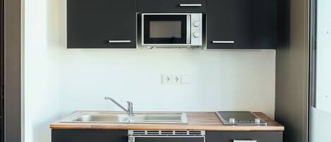 Une cuisine compacte équipée d’un four à micro-ondes, d’un évier et d’une cuisinière.