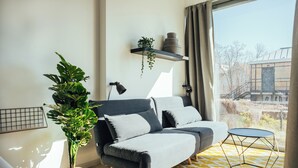 Ein modernes Wohnzimmer mit grauem Sofa, rundem Couchtisch und einer Topfpflanze.