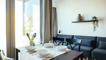Un comedor con una mesa dispuesta para cuatro, un sofá gris y una estantería con adornos.