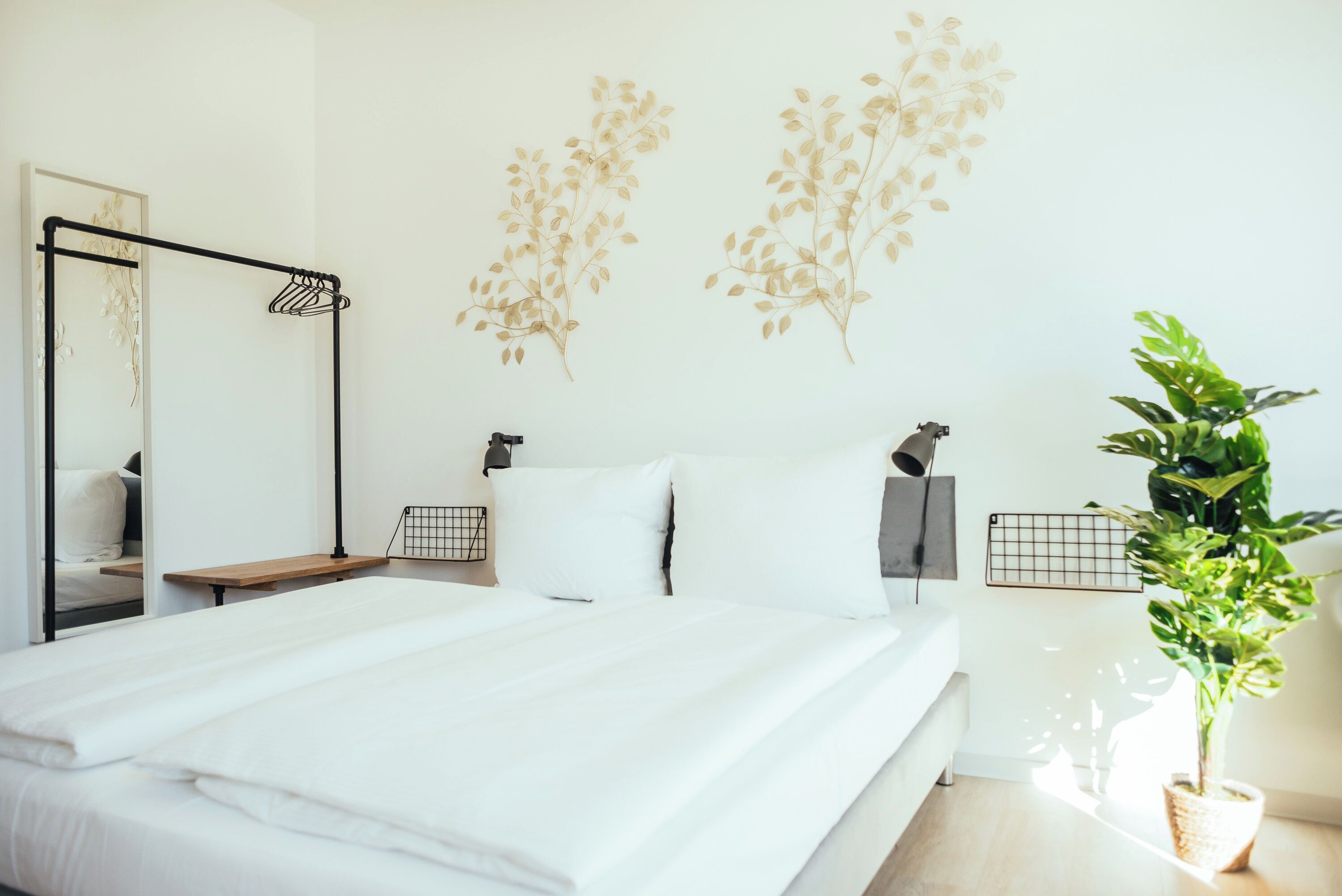 Un dormitorio moderno con una cama grande, una mesita de noche, un espejo y una planta en maceta.