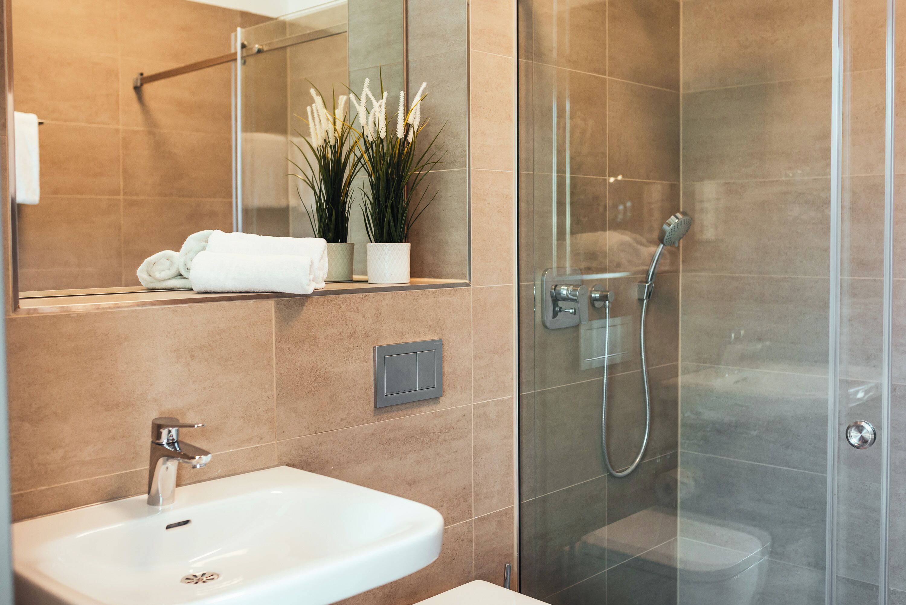 A modern bathroom with a glass shower enclosure, a white sink, and a mirror above the sink.