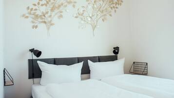A neatly made bed with white linens, a dark headboard, and two wall-mounted lamps.