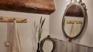 Un baño con tocador de madera, lavabo de piedra, espejo y toalla colgada en un gancho.