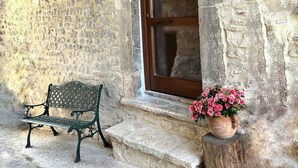 Un edificio de piedra con puerta de madera y escalones que conducen a él. Un banco está colocado afuera.