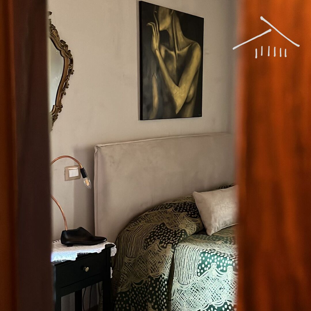 Un dormitorio con una cama, una mesita de noche, una lámpara y un cuadro en la pared.