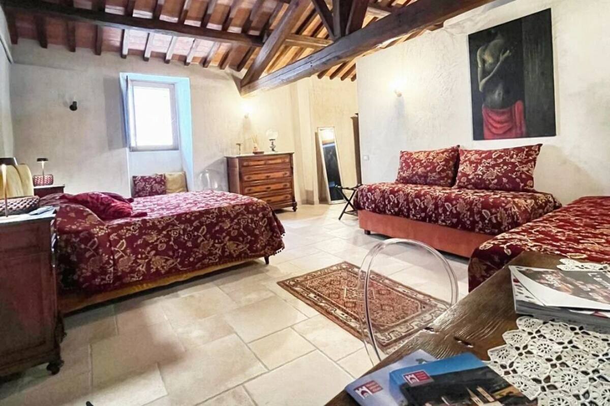 A bedroom with two beds, a wooden ceiling, a large window, a dresser, and a mirror.