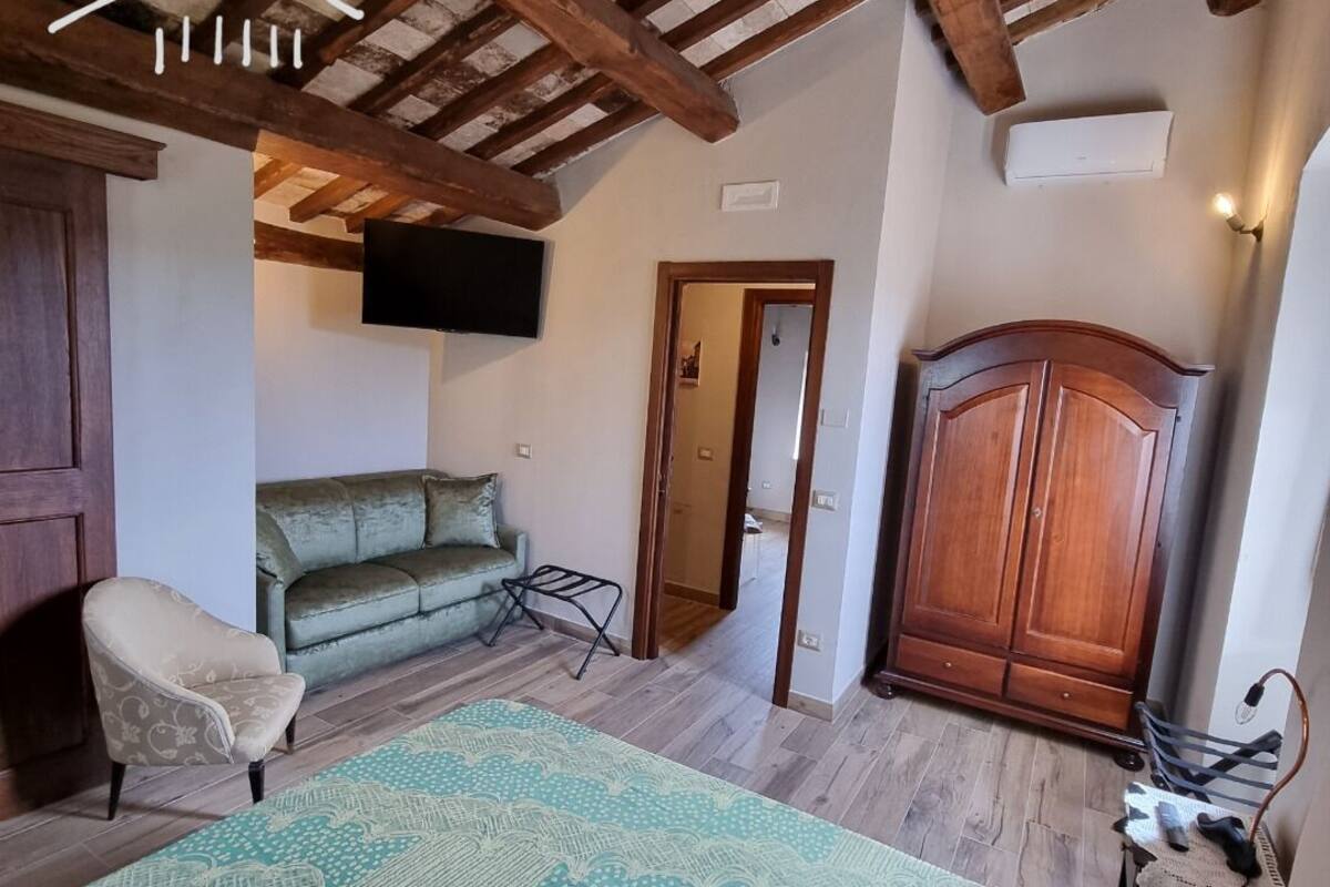 A room with a wooden ceiling, a sofa, a cabinet, and a television.