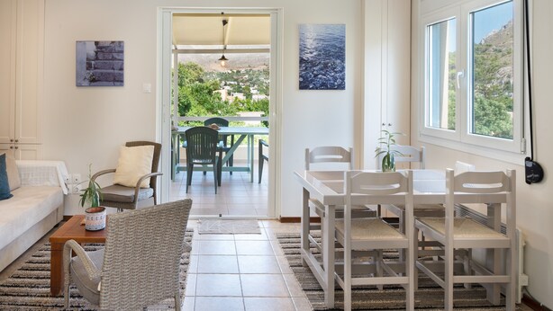 Un salon comprenant un canapé, des fauteuils, une table à manger et donnant sur l’extérieur.