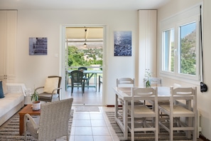 Una sala de estar con un sofá, sillas, una mesa de comedor y vistas al exterior.