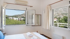 Une chambre à coucher avec un lit, une fenêtre, un miroir et une vue sur une colline.