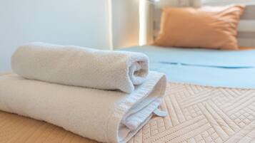 A neatly folded white towel on a beige quilted bedspread.