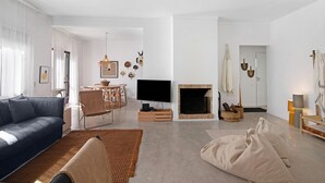A modern living room with a sofa, TV, fireplace, and a dining area.