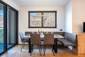 Un comedor con mesa, sillas, un banco, un ventanal con vistas y un televisor en la pared.