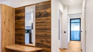 Een moderne badkamer met een houten accentmuur, een grote spiegel en een houten wastafelmeubel.