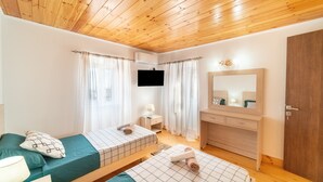 A bedroom with two beds, a wooden ceiling, a TV, a mirror, and a wooden wardrobe. - Bekiris Traditional Inn Country House with Private Terrace, Air Conditioning & Wi-Fi (Lefkimi)