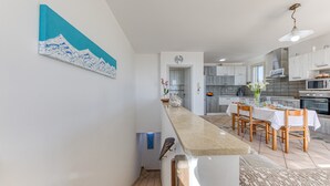 Een moderne keuken met een centraal eiland, houten stoelen en een eettafel.