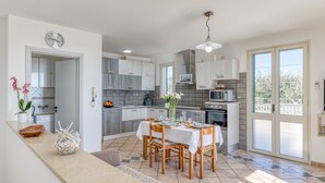 Een moderne keuken met een eethoek, een klok en een uitzicht door de glazen deuren.