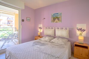 Et soveværelse med en seng, to sengeborde, et natbord, et vindue med udsigt til en balkon og et billede på væggen.