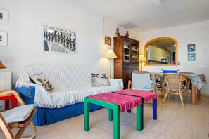 A living room with a sofa, a table, wicker chairs, a cabinet, and a mirror.