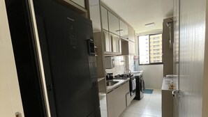 A kitchen with a black refrigerator, white cabinets, a window, and a tiled floor. - I rent an entire apartment in Aracaju. (Aracaju)